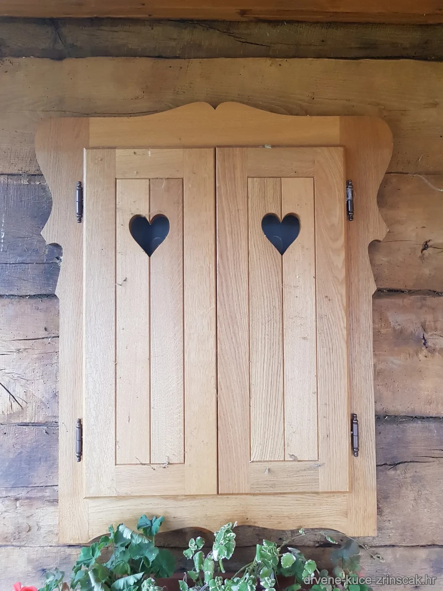 Drveni prozorski kapci s izrezanim srcima na rustikalnoj fasadi